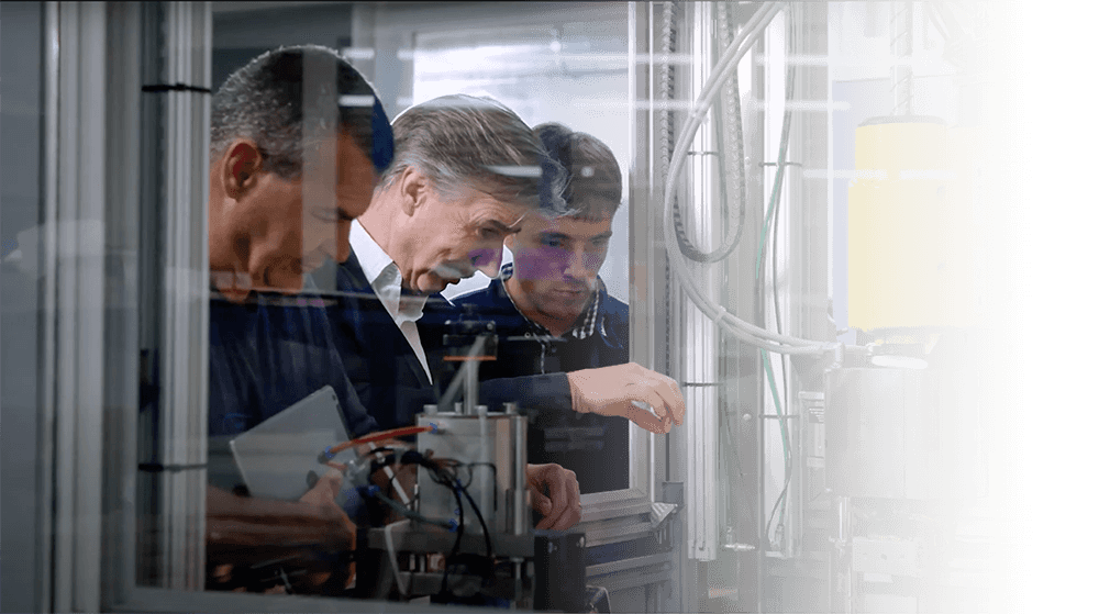 Drei Männer prüfen eine Maschine